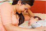 Beautiful young mother in bed smiling at her sleeping baby.