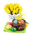 Easter eggs in basket with yellow tulips. Isolated on white background