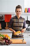 Portrait of happy young housewife peeling corn