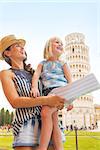 Happy mother and baby girl sightseeing in front of leaning tower of pisa, tuscany, italy