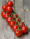 Perfect Ripe Cherry Tomatoes on Stem In a Row on Rustic Wooden background