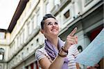 Portrait of happy young woman with map pointing near uffizi gallery in florence, italy