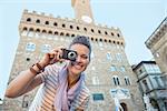 Happy young woman taking photo in front of palazzo vecchio in florence, italy