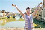 Happy young woman standing on bridge overlooking ponte vecchio in florence, italy and rejoicing