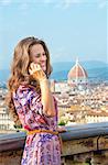 Happy young woman talking cell phone against panoramic view of florence, italy