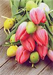 Arrangement of Bunch Magenta Tulips with Yellow and Green Spotted Easter Eggs closeup on Wooden background. Retro Styled