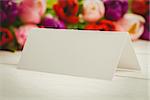 Close up of colorful tulips and white card on wooden table