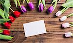 Tulips forming frame around white card on wooden table