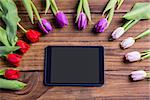 Tulips forming frame around tablet on wooden table