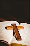 Open bible with crucifix icon on wooden table