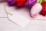 Bunch of tulips and white card on wooden table