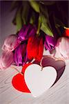 Bunch of tulips and heart card on wooden table