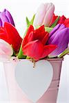 Bunch of tulips and heart card on white background