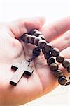 Hand holding wooden rosary beads in close up