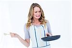 Woman holding frying pan and wooden spoon on white background