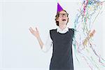 Happy geeky hipster wearing a party hat on white background