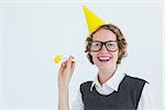 Geeky hipster in party hat with horn on white background