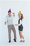 Geeky couple dancing with party hat on white background