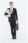 Geeky hipster businessman holding briefcase and teddy on white background