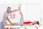 Physiotherapist doing leg stretching to his patient in medical office