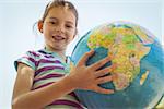 Cute little girl holding globe on a sunny day
