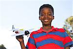 Little boy playing with toy airplane on a sunny day