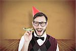 Geeky hipster in party hat with horn against yellow background with vignette