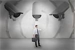 Businessman checking the time while holding briefcase against sheet spiral on grey wall