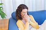 Sick woman blowing her nose in the living room