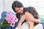 Smiling girl offering flowers to her mother in the living room