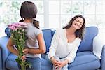 Cute girl offering flowers to her mother in the living room