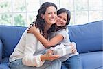 Happy mother and daughter hugging and smiling at camera in the living room