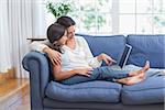 Happy mother and daughter sitting on the couch and using laptop in the living room