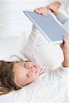 Smiling girl using tablet in bed