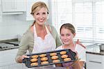 Mother and daughter making cookies together at home in the kitchen