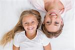 Mother and daughter smiling at camera at home in the bedroom