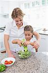 Mother and daughter preparing salad at home in kitchen