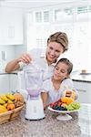 Mother and daughter making a smoothie at home in kitchen