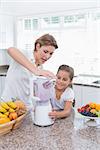 Mother and daughter making a smoothie at home in kitchen