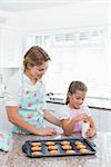 Mother and daughter with hot fresh cookiesat home in kitchen