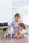 Mother and daughter filling pot with water at home in kitchen