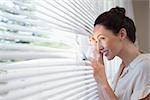 Woman peeking through the blinds from inside