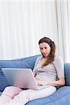 Casual woman using laptop on couch at home in the living room