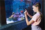 Cute girl looking at fish tank at the aquarium