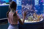 Cute girl looking at fish tank at the aquarium