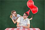 Geeky hipster couple celebrating his birthday  against green chalkboard