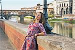Relaxed young woman on embankment near ponte vecchio in florence, italy