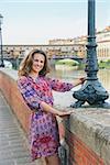 Happy young woman on embankment near ponte vecchio in florence, italy