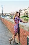Full length portrait of happy young woman on embankment near ponte vecchio in florence, italy