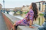 Relaxed young woman sitting near ponte vecchio in florence, italy